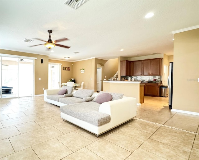 tiled living room featuring a textured ceiling, ornamental molding, and ceiling fan