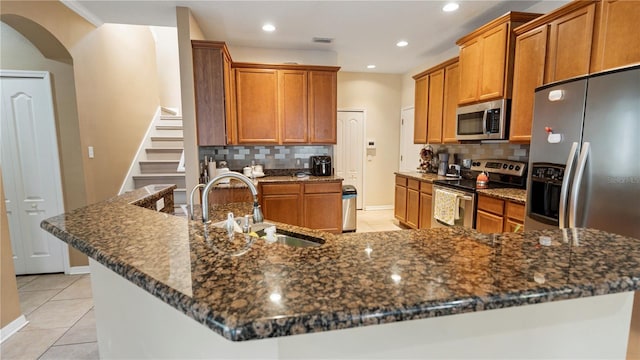4110 Huntingdale Ct, Wesley Chapel, FL 33543 - kitchen with stainless steel appliances, a sink, light tile patterned flooring, tasteful backsplash, and brown cabinets