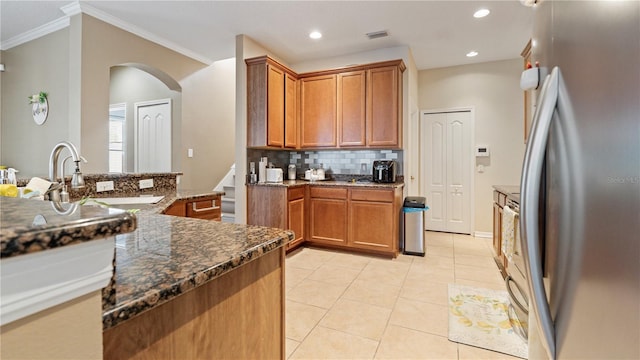 4110 Huntingdale Ct, Wesley Chapel, FL 33543 - kitchen featuring freestanding refrigerator, tasteful backsplash, a sink, arched walkways, and light tile patterned flooring