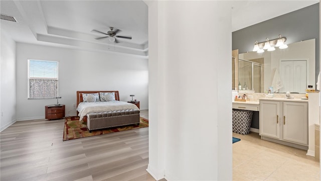 4110 Huntingdale Ct, Wesley Chapel, FL 33543 - bedroom featuring connected bathroom, light wood-style floors, a raised ceiling, and baseboards