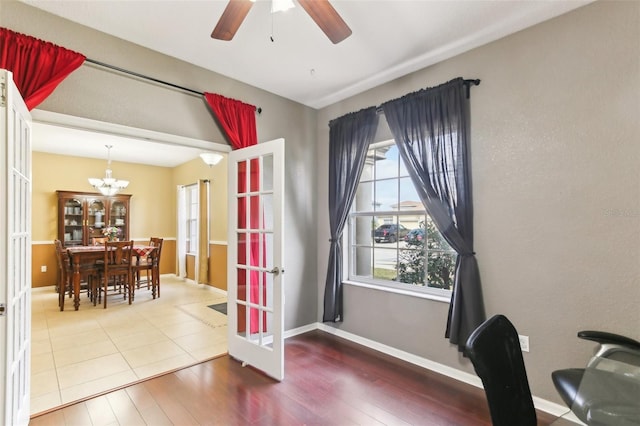 office space with ceiling fan with notable chandelier, hardwood / wood-style floors, and french doors