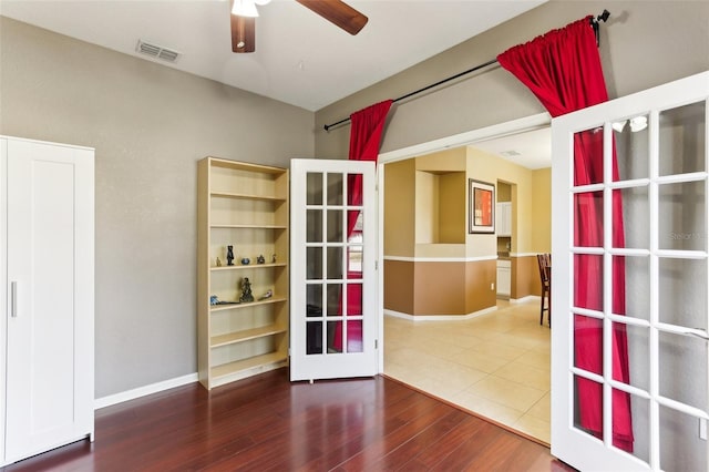 empty room with wood-type flooring, french doors, and ceiling fan