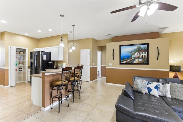 kitchen featuring pendant lighting, light tile patterned floors, a breakfast bar area, white cabinetry, and light stone counters