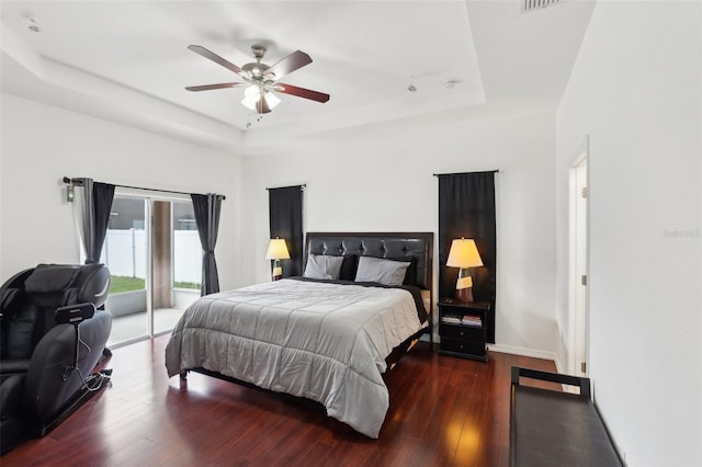 bedroom featuring dark hardwood / wood-style flooring, a raised ceiling, and access to exterior