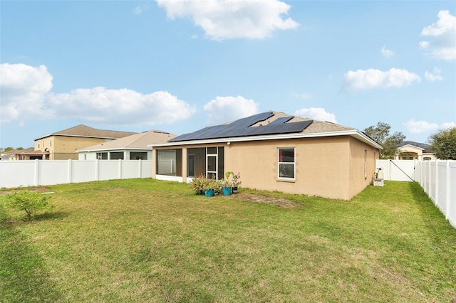 rear view of house featuring a lawn, a sunroom, and solar panels