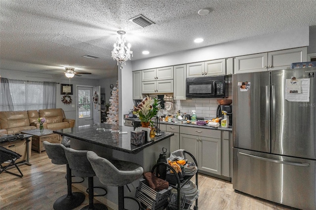 kitchen with a kitchen island, gray cabinetry, stainless steel fridge, and light hardwood / wood-style floors