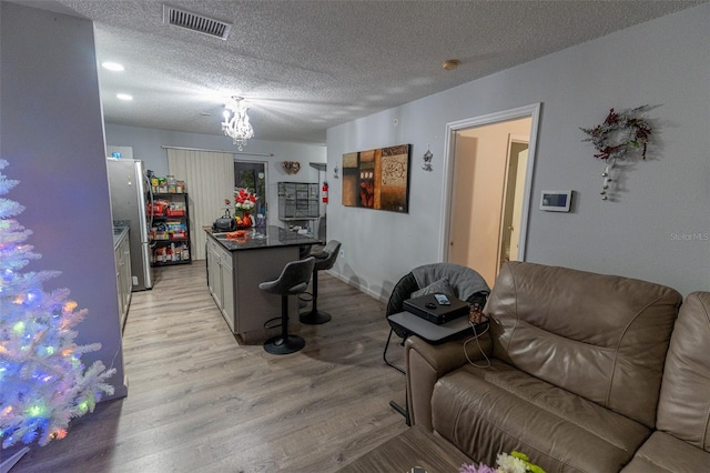 living room featuring a notable chandelier, a textured ceiling, and light wood-type flooring