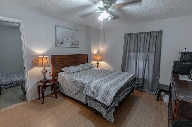 bedroom featuring ceiling fan, light hardwood / wood-style flooring, and a textured ceiling