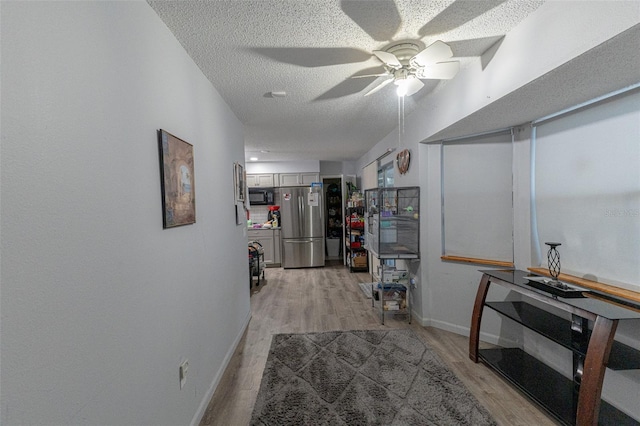 hallway with a textured ceiling and light wood-type flooring