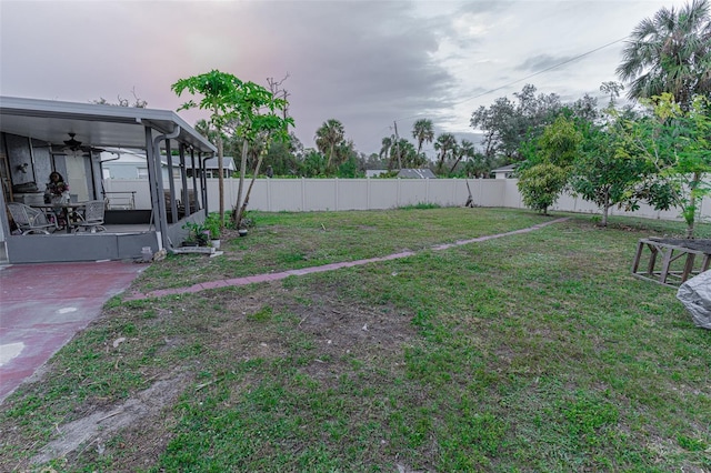 view of yard featuring a sunroom, ceiling fan, and a patio area