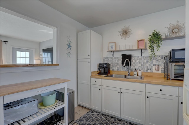 kitchen featuring white cabinetry, sink, tasteful backsplash, and light tile patterned flooring