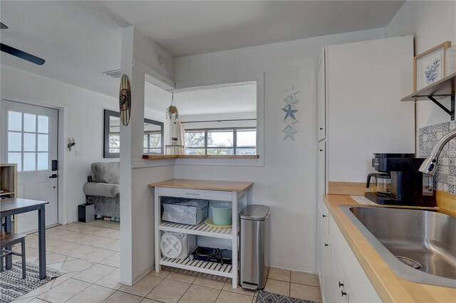 kitchen featuring white cabinets, sink, and light tile patterned floors