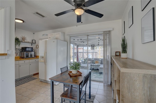 dining room with light tile patterned flooring, ceiling fan, and a textured ceiling