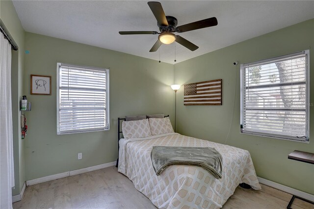 bedroom featuring multiple windows, light hardwood / wood-style floors, and ceiling fan