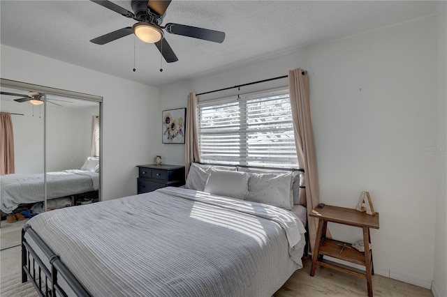 bedroom featuring ceiling fan, a closet, a textured ceiling, and light hardwood / wood-style flooring