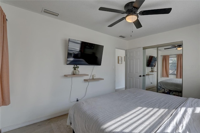 bedroom with light hardwood / wood-style flooring, ceiling fan, and a closet