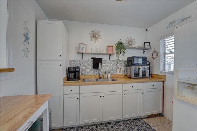 kitchen featuring black microwave, white cabinetry, a sink, and open shelves