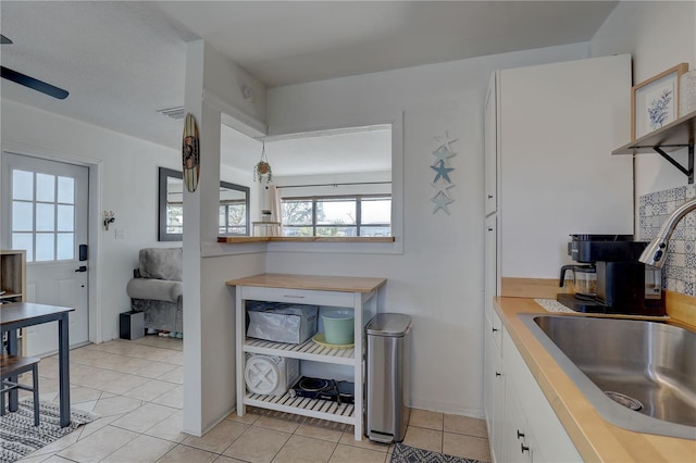 interior space featuring light tile patterned floors, white cabinetry, visible vents, light countertops, and a sink