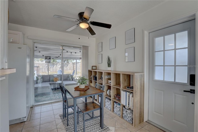 dining space with light tile patterned floors, ceiling fan, and a textured ceiling