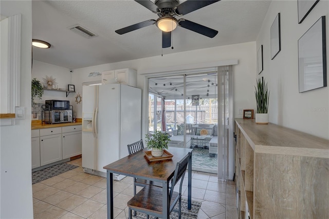 dining area featuring light tile patterned flooring, a ceiling fan, and visible vents