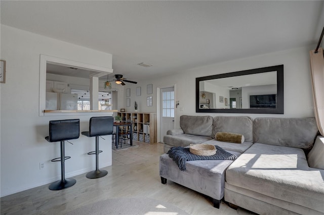 living area featuring light wood-style floors, baseboards, and ceiling fan