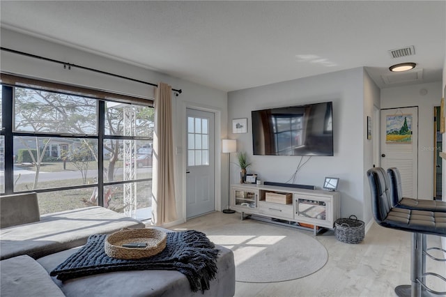 living room featuring visible vents, baseboards, and light wood finished floors