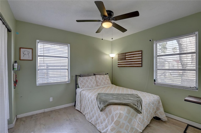 bedroom with baseboards, light wood-type flooring, and a ceiling fan