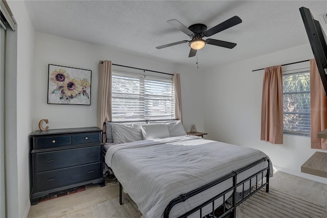 bedroom with a ceiling fan, light wood-style floors, and multiple windows