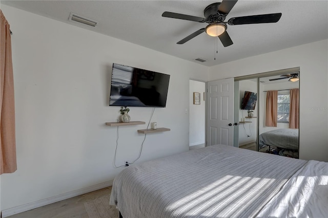 bedroom with light wood-style flooring, visible vents, ceiling fan, and a closet