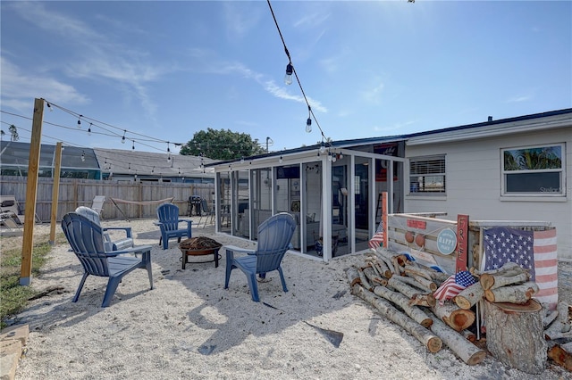 view of patio / terrace featuring a sunroom, fence, and a fire pit