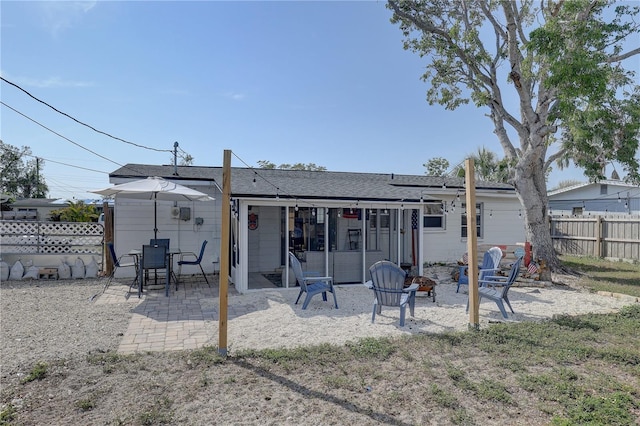 rear view of house featuring a patio, fence, and an outdoor fire pit