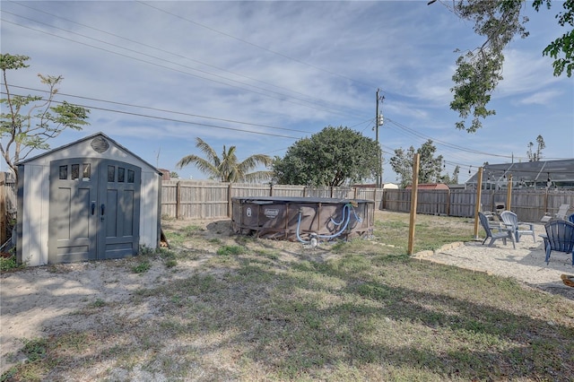 view of yard featuring a patio area, a fenced backyard, an outdoor structure, a storage unit, and a fenced in pool
