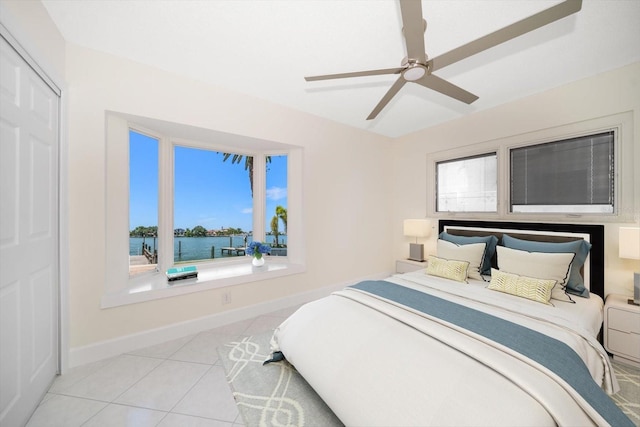 tiled bedroom with a water view and ceiling fan