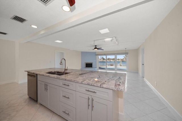 kitchen with sink, stainless steel dishwasher, light tile patterned floors, ceiling fan, and light stone counters