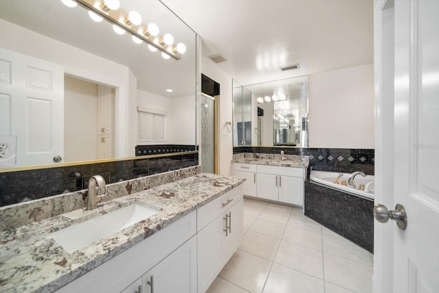 bathroom with tile patterned flooring, vanity, and tiled bath