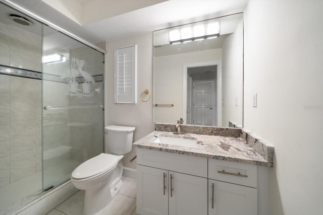 bathroom featuring vanity, a shower with shower door, tile patterned floors, and toilet