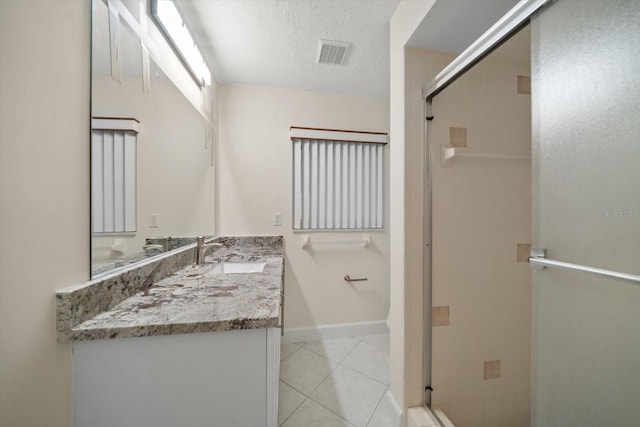 bathroom with vanity, a shower with shower door, tile patterned floors, and a textured ceiling