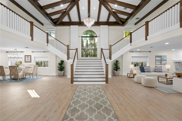 entryway with an inviting chandelier, high vaulted ceiling, and light wood-type flooring