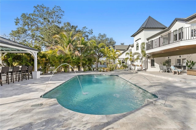 view of swimming pool with a patio, a gazebo, pool water feature, and exterior bar