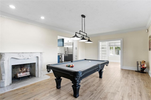 rec room with crown molding, pool table, a premium fireplace, and light hardwood / wood-style floors