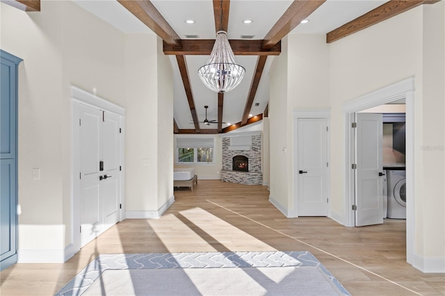 hall with beam ceiling, washer / dryer, light hardwood / wood-style flooring, and an inviting chandelier