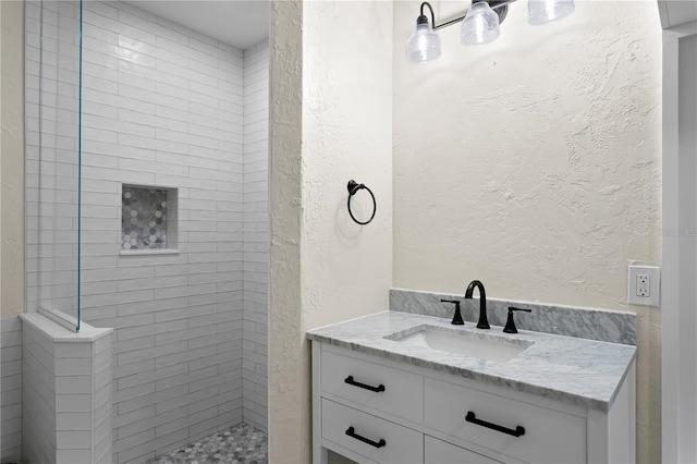 bathroom with vanity and tiled shower