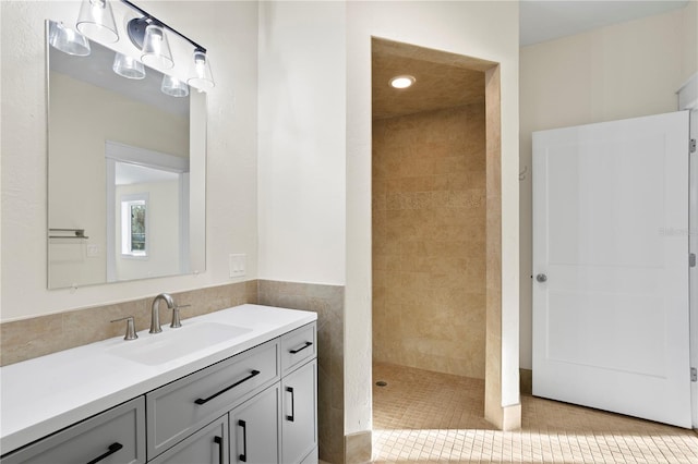 bathroom featuring tile patterned flooring, vanity, and tiled shower