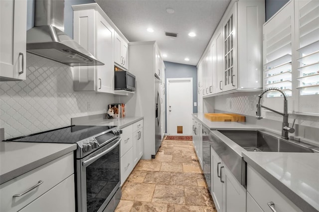 kitchen with sink, stainless steel appliances, white cabinets, decorative backsplash, and wall chimney exhaust hood