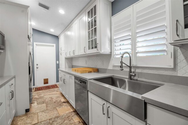 kitchen featuring sink, stainless steel dishwasher, white cabinets, and backsplash