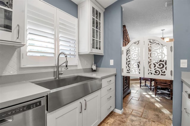 kitchen with white cabinetry, dishwasher, sink, backsplash, and a textured ceiling