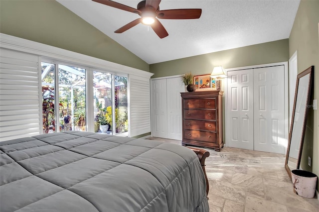 bedroom with ceiling fan, a textured ceiling, vaulted ceiling, and multiple closets