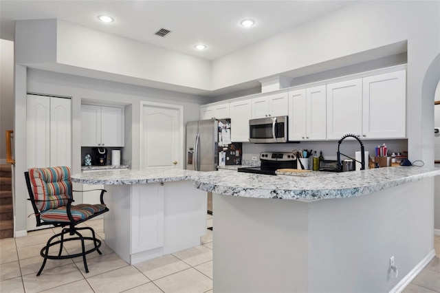 kitchen featuring white cabinetry, stainless steel appliances, a kitchen island, and a breakfast bar area