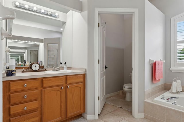 bathroom with tile patterned flooring, vanity, tiled bath, and toilet