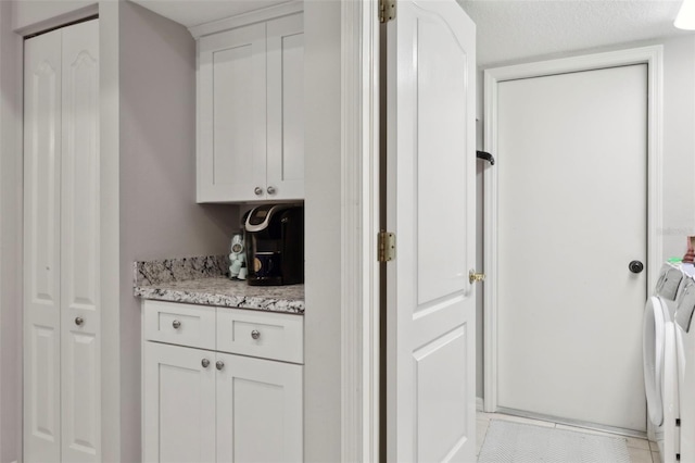 bar with washing machine and dryer, light stone countertops, a textured ceiling, white cabinets, and light tile patterned flooring